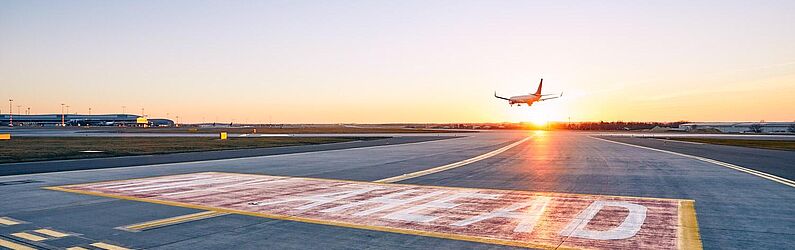 A landing airplane flying towards a setting sun