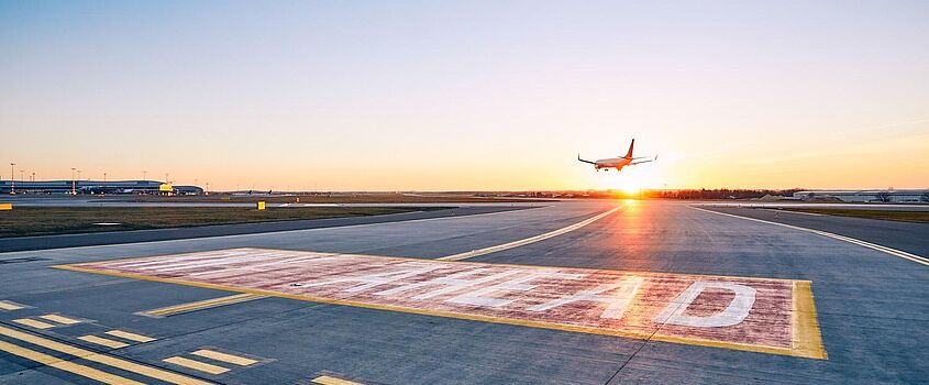 A landing airplane flying towards a setting sun